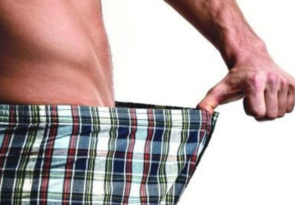 一个男人看着他的裤子，想要增大阴茎